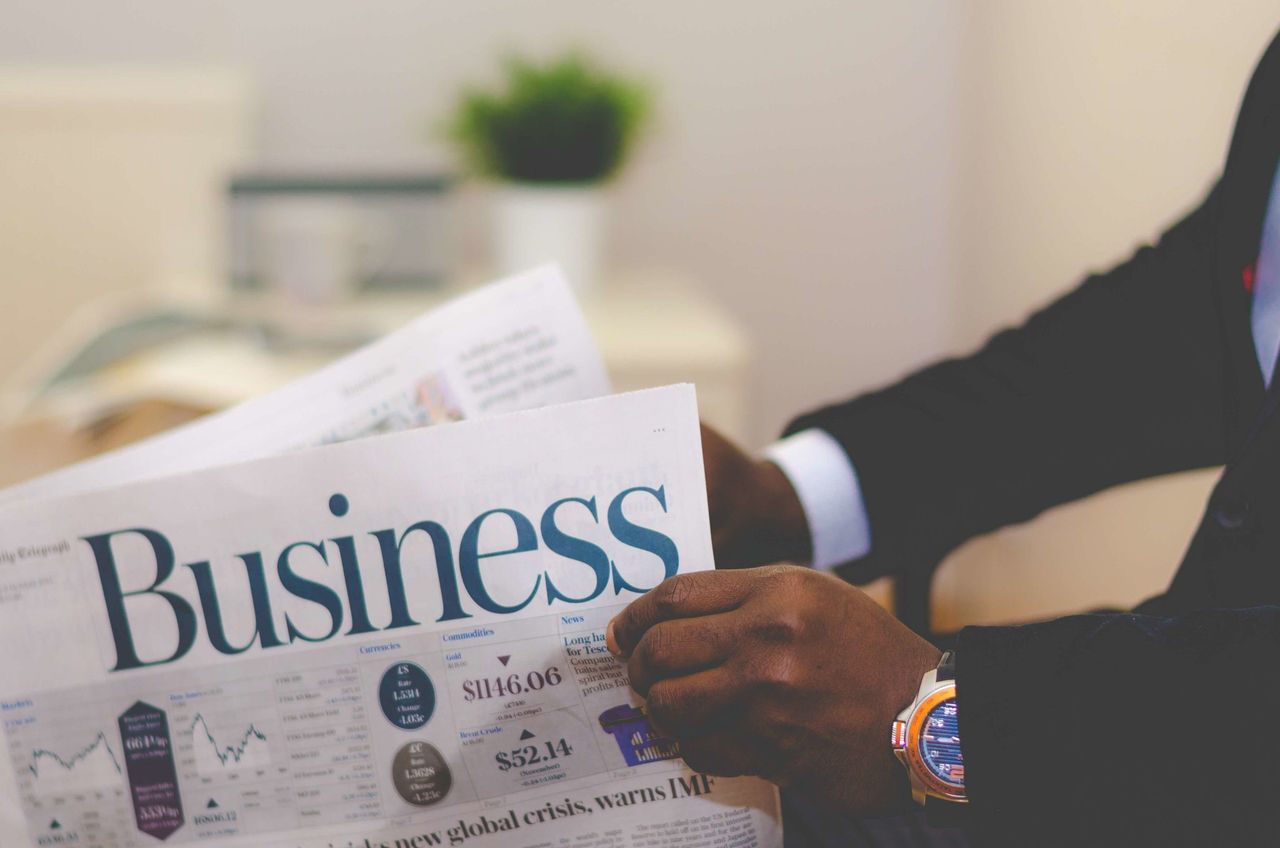 About Close-up of a businessman reading a newspaper indoors, focusing on business headlines.